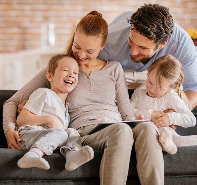 A mother and father sitting on a couch with their children