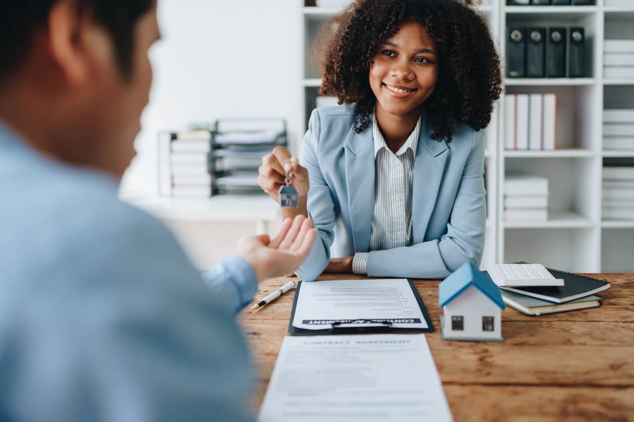 A young woman hands keys to a new homeowner