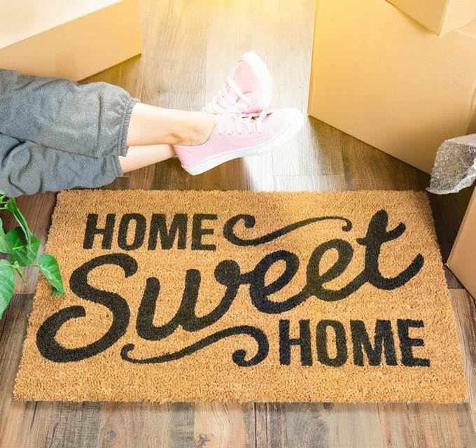 A woman sitting by a doormat that says 