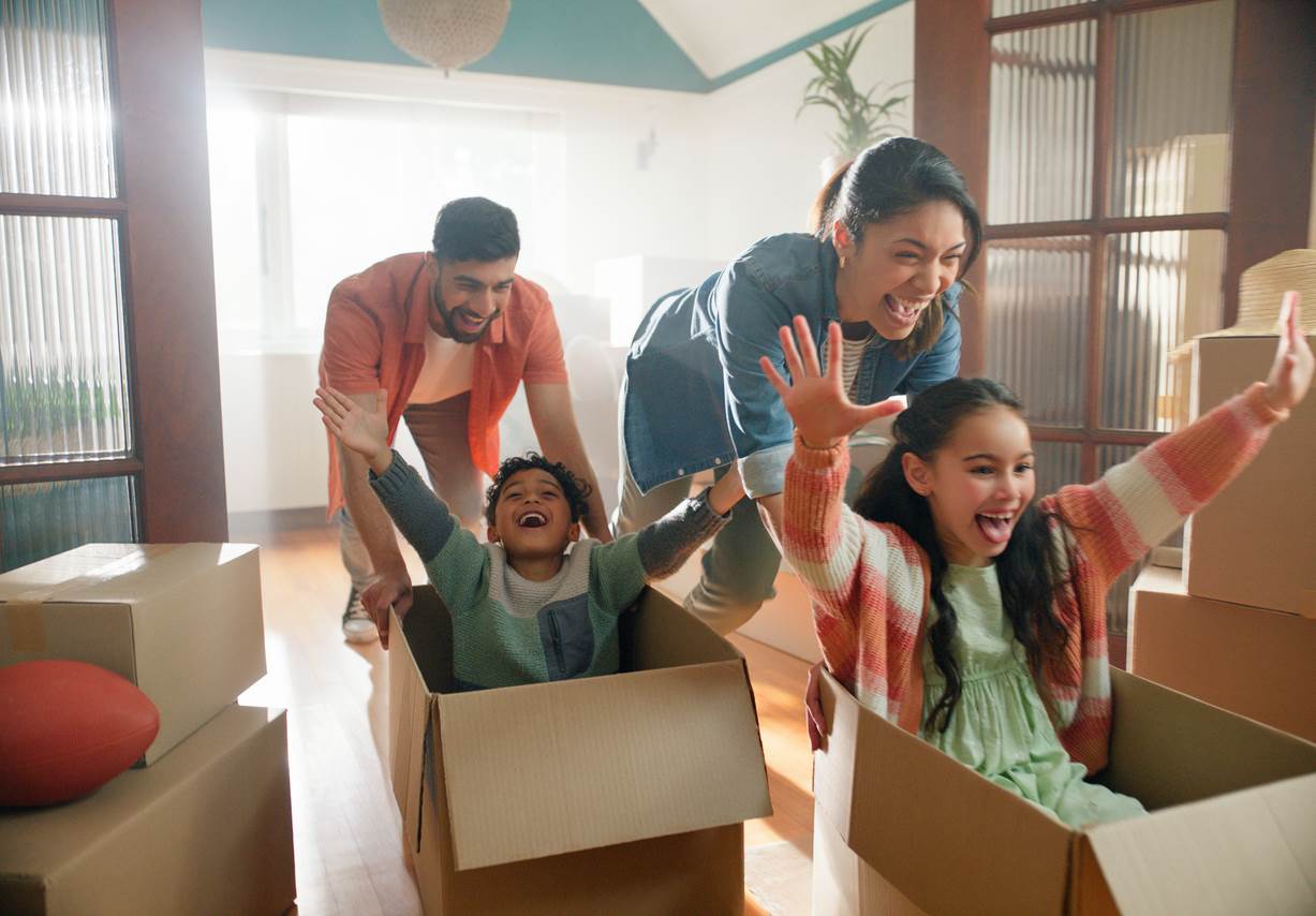 A mother and father push kids around an empty house in boxes