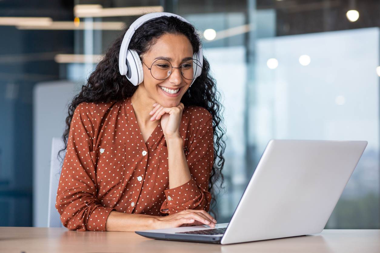 A woman looking at a laptop with headphones on