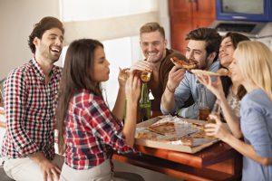 Friends eating pizza together in the kitchen